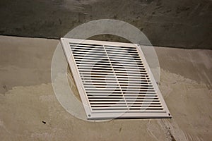 Ventilation grille in the apartment without finishing. concrete walls with white air grille