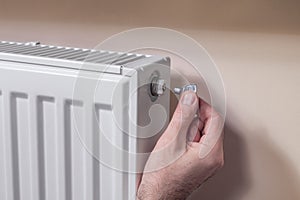 Venting the radiator. The man`s hand holds a special key which he inserts into the vent valve.