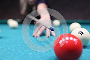 Venturous woman ready to hit red ball on blue pool table photo