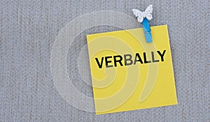 VERBALLY - words on yellow paper with clothespin on gray background