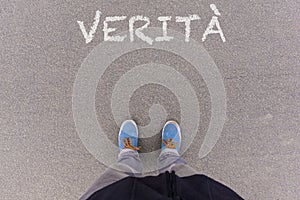 Verita, Italian text for Truth text on asphalt ground, feet and