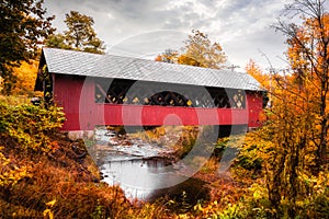 Vermont covered bridge surrounded by colorful fall foliage. photo