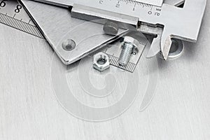 Vernier caliper, screws and bolt on scratched metal background