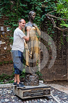 Verona, Italy - August 6, 2019: Tourists take photo with bronze statue of Guilietta, from romeo and juiliet