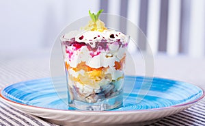 verrin glass with Russian salad herring under fur coat from vegetables on blue plate