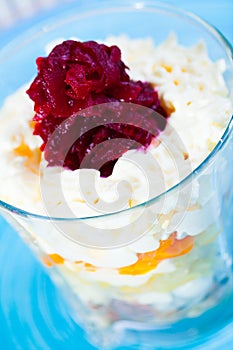 Verrin glass with Russian salad herring under fur coat from vegetables on blue plate