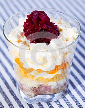 verrin with salad herring under fur coat from vegetables on striped tablecloth