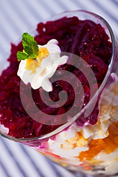 Verrin with salad herring under fur coat from vegetables on striped tablecloth