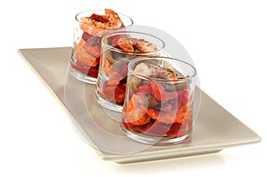 Verrines with chorizo shrimp and peppers placed on a dish on a white background