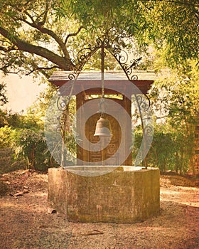 Old water well with ornate iron scrollwork & bell photo