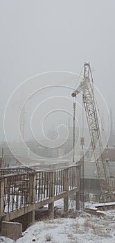 Vertcal Vintage Style Photo of a Cunstruction Site with Cranes in cold Winter fog