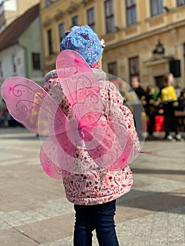 Vertical ack view of a little girl wearing pink butterfly wings