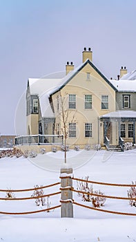 Vertical Adorable homes beyond a rope fence on the snow covered ground in winter