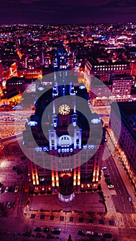 Vertical aerial view of a lit-up cityscape at night with a prominent clock tower and urban streets in Liverpool, UK