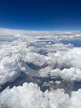 Vertical aerial view of a rural landscape enveloped in puffy clouds in blue sky background