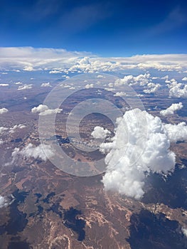 Vertical aerial view of a rural landscape enveloped in puffy clouds in blue sky background