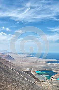 Vertical aerial view to industrial colorful pools, desert mountains and ocean