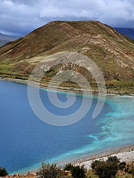 Vertical aerial view of Yamdrok Yumso lake in Tibet, China under a cloudy sky