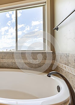 Vertical Alcove bathtub with antiqued marble tiles and deck mounted widespread faucet