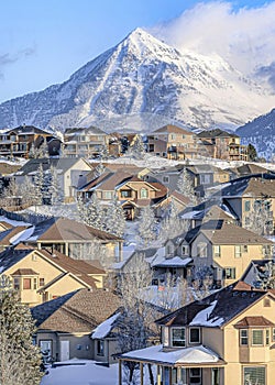 Vertical Alpine Utah in winter with houses against snowy mountain and cloudy blue sky photo