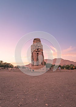 Vertical of the ancient Colossi of Memnon in Luxor, Egypt captured at sunset