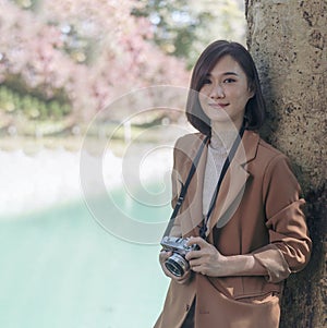 Vertical Asian Women with vintage film camera take a photo. Smiling female photographer look at photo from professional camera