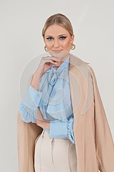 Vertical attractive confident blond businesswoman in formal stylish suit with jacket on shoulder posing in white studio