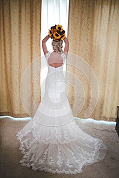 Vertical back view of a bride holding a bouquet over her head before throwing it