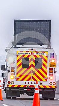 Vertical Back view of an emergency vehicle on the road with traffic cones and cars