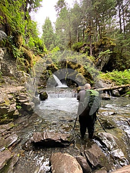 Vertical back view of a professional photographer shooting the Virgin Falls in Girdwood, Alaska