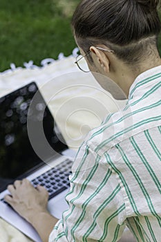 Vertical back view with selective focus of man working as freelancer on laptop in the home garden