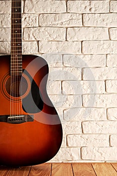 Vertical backdrop with an acoustic guitar on the wooden floor near brick wall