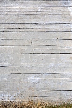 Vertical background of an apparent concrete wall with grass at the base