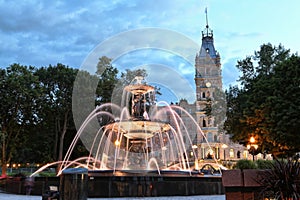 Vertical of a beautiful fountain against a medieval castle at twilight in Old Quebec, Canada