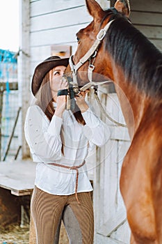 Vertical beautiful horse woman cowgirl equestrienne kissing companion. Breeches, shirt. Cleaning brushing grooming mane