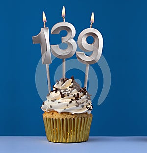 Vertical birthday card with cupcake - Lit candle number 139 on blue background