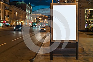 Vertical blank glowing billboard on night city street. In background buildings and road with cars. Mock up.