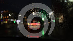Vertical. Blurred background of night city traffic through wet car windshield.