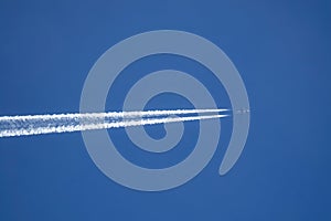 VERTICAL BOTTOM UP: Airplane flies across the sky, leaving a long white trail.