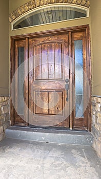 Vertical Brown wooden front door of home with sidelights and arched transom window