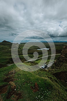 Vertical of a car driving along a trail on Skie island in Scotland captured under a grey cloudy sky