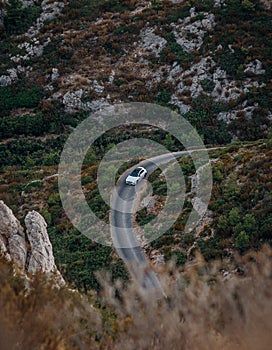 Vertical of a car on the road through rocks covered with lush greenery in the Massif des Calanques