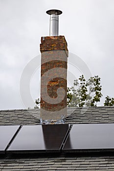 Vertical of a chimney and solar panels on an old New England home.