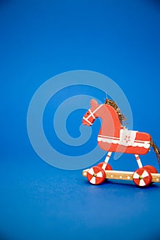 Vertical close shot of a red wooden horse toy with a blue background