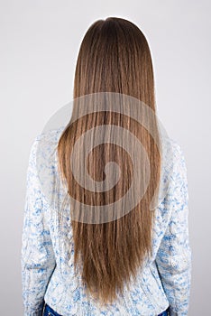Vertical close up back behind rear view photo of woman demonstrating showing her long but problematic hair isolated grey