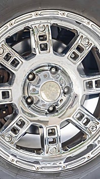 Vertical Close up of the black rubber tire of an off roading truck with shiny chrome mags