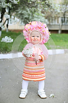 Vertical close-up photo of a little girl with a sprig of blooming cherry in hands