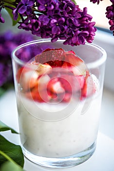 Vertical close-up picture of layered strawberry homemade italian creamy dessert panna cotta with fresh berries in glass with