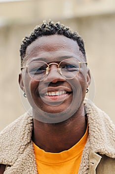 Vertical close up portrait of african american teenage boy looking at camera smiling and laughing at univesity campus