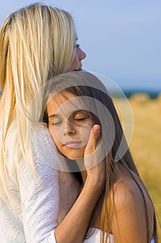 Vertical close-up portrait of two beautiful girls on a background of a wheat field